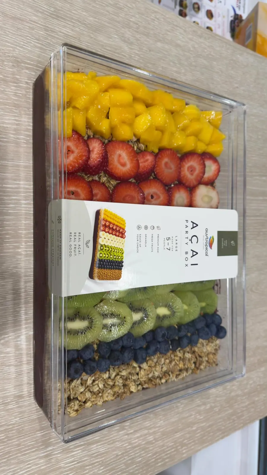 A large Açaí Party Box from above: açaí under rows of mango, strawberry, kiwi, blueberry and granola.